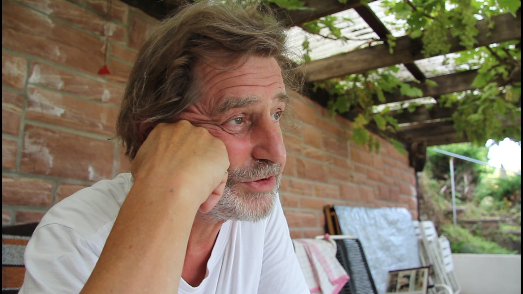 The film-maker's father sitting under a vine-covered pergola